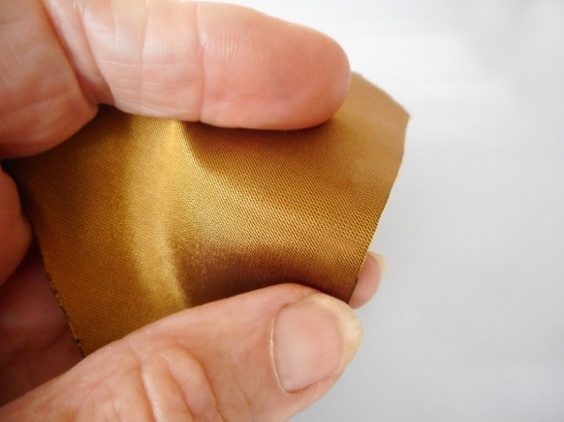 Treated silk held between fingers showing a soft, flexible, mark-free finish